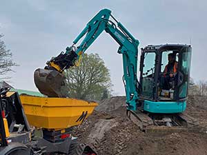 Kobelco Digger sat on soil loading a dumper